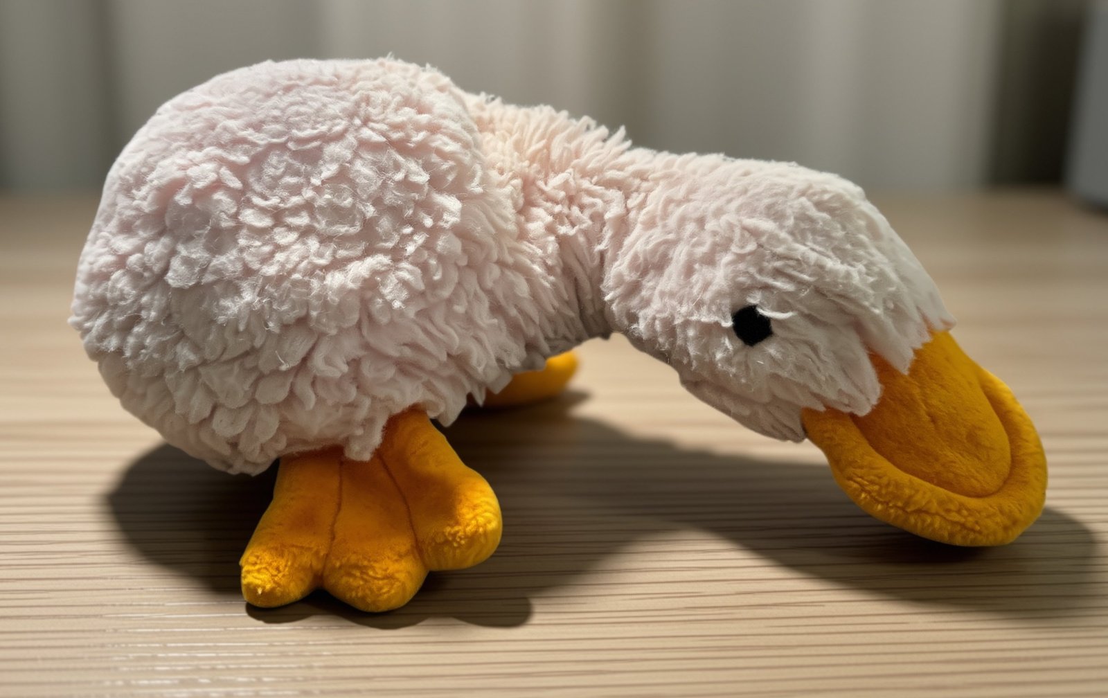 The original pink stuffed platypus, faded and well loved, with a big orange bill and orange webbed feet